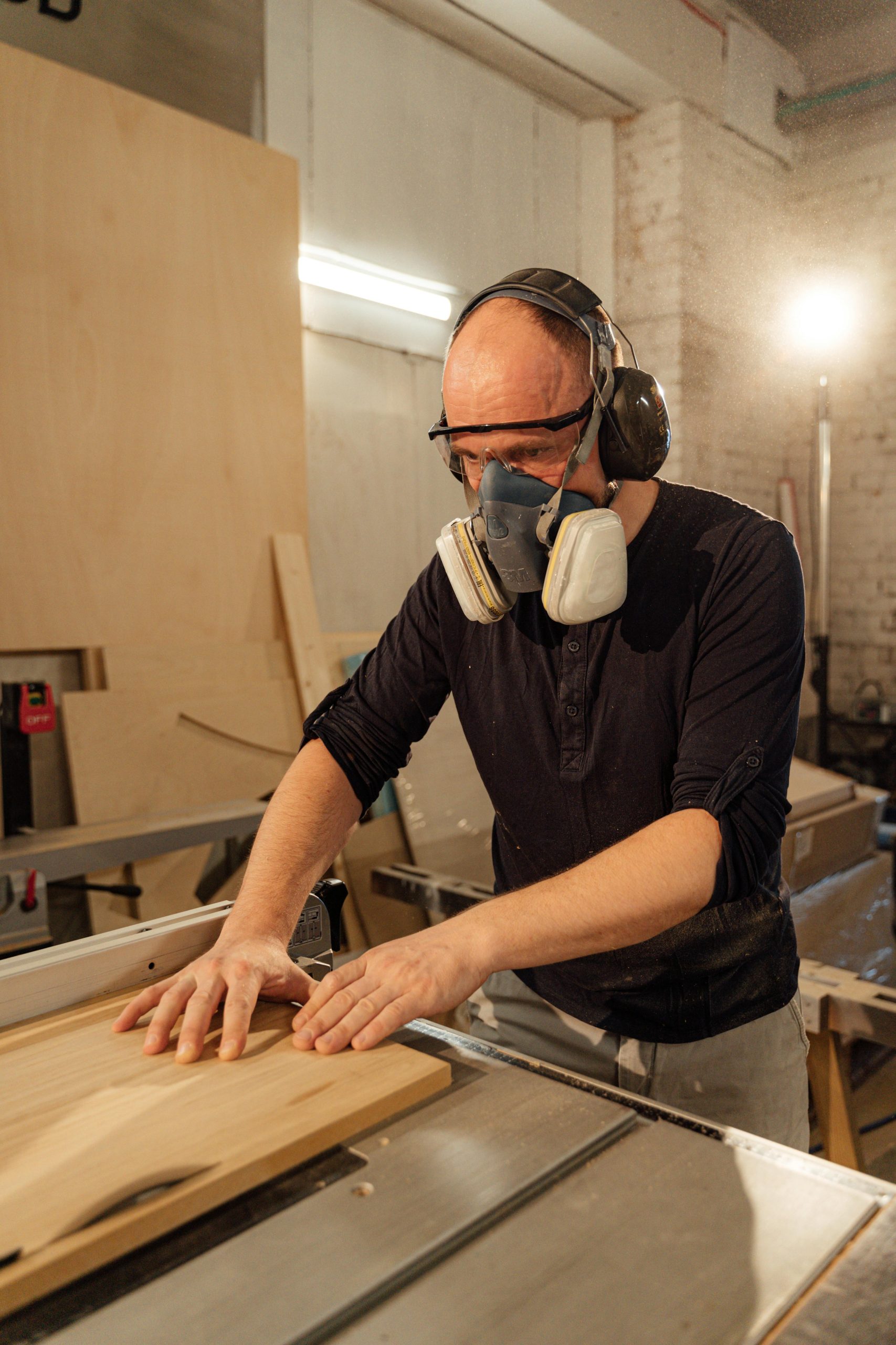An adult male woodworker shaping wood with precision in a well-lit workshop.